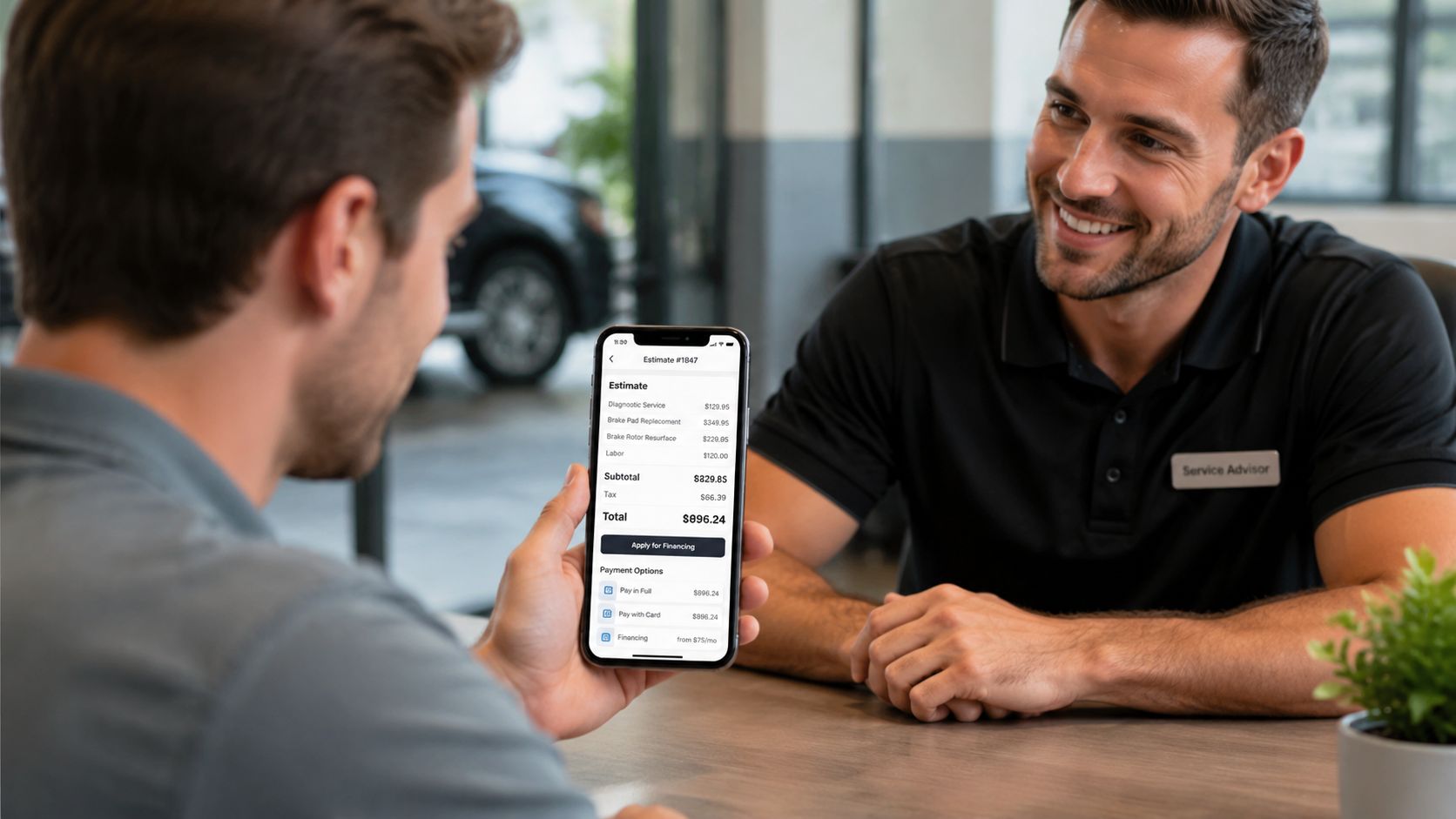 A service advisor discussing a mobile auto repair estimate with a customer at a dealership office.